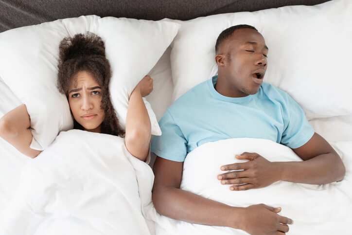 image of a man snoring and his partner being upset